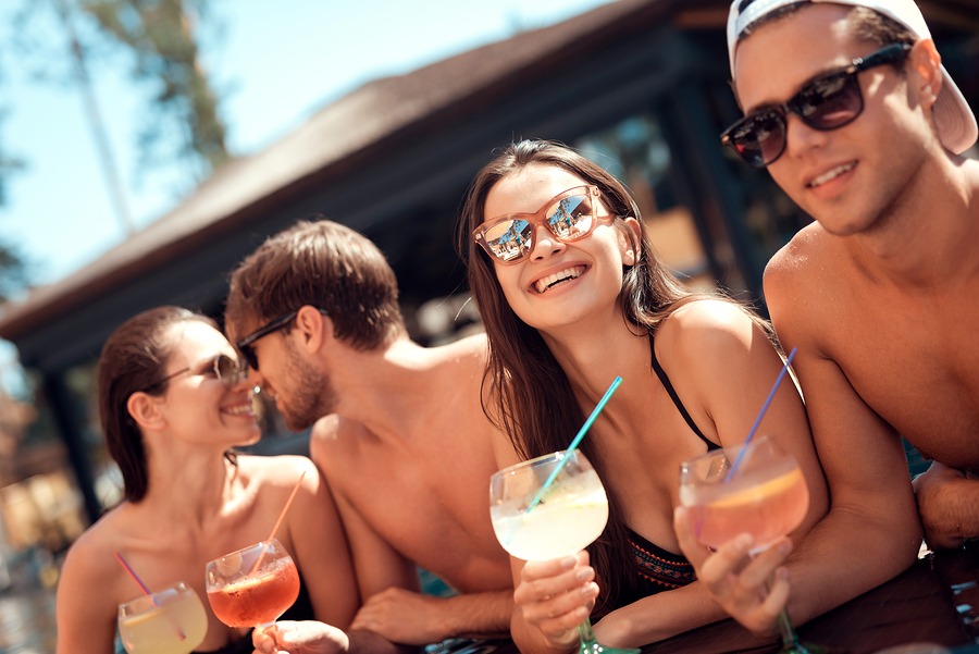 group of young friends drinking cocktails in spa hot tub pool