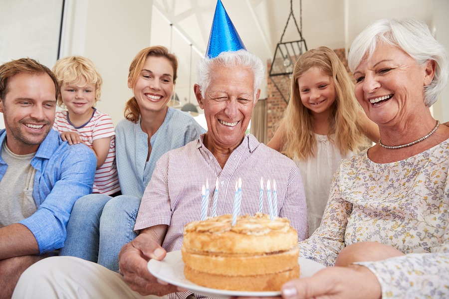 family giving cake to senior man