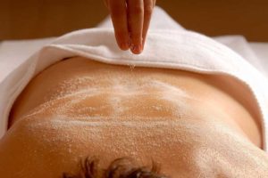 a person receiving a salt glow body scrub