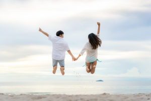 Happy couple tourists jumping on beach vacations. Travel concept of young couple cheering for summer holidays showing success, happiness, and joy on perfect white sand tropical beach under the sun. Unforgettable New Year's Eve Getaways & Celebrations … Best Getaway gift card for husband valentines ideas for him in New York City