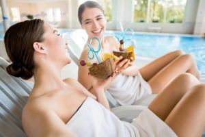 Laughing girls with tropical cocktails enjoying rest at luxurious spa resort - New York City Getaway Package - gifts card for him & Valentines day gifts for her, Facials, Spa Massage, body scrubs in New York NYC