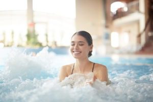 Portrait of beautiful young woman smiling happily while enjoying bubbly hot tub in SPA, copy space - family getaways for new year's eve 2021 things to do on New Years for boyfriend in New York City, Manhattan NYC, Gift Card